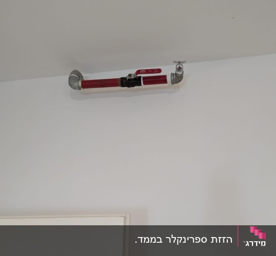 צינור כיבוי אש מותקן על תקרה לבנה
